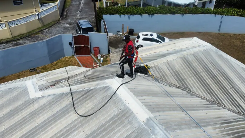 Technician pressure washing a galvanized roof